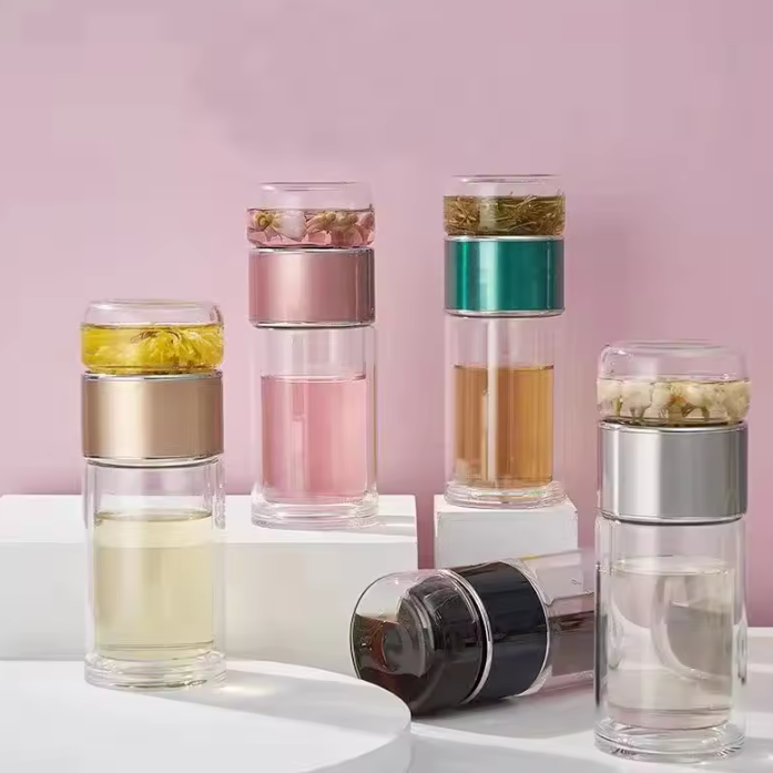 Set of tea glass infuser bottles with different colored layers on a pink background